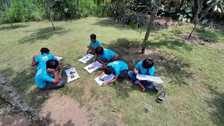 Students making hand-painted literacy campaign banners outdoors